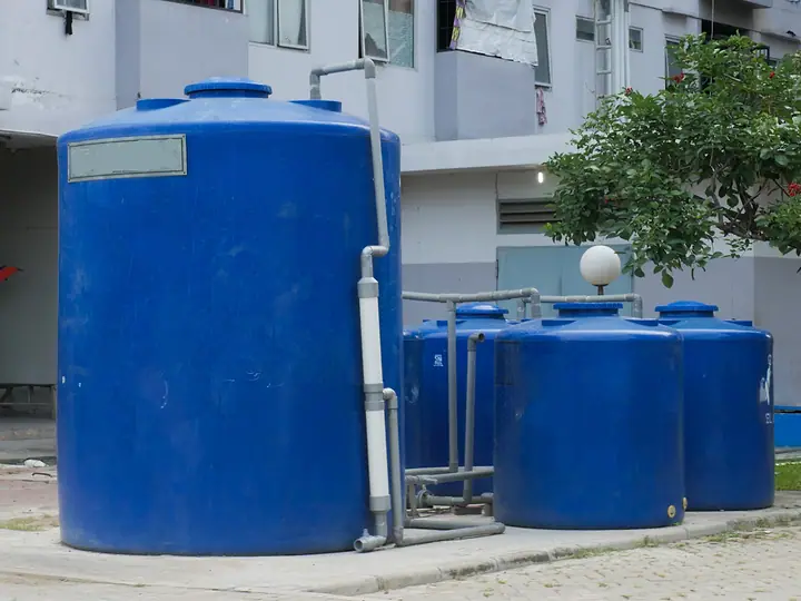 Caixas d’água azuis ao lado de um prédio residencial
